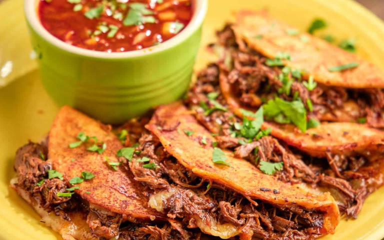 Tacos de birria servidos con consomé en Roosevelt Avenue Queens